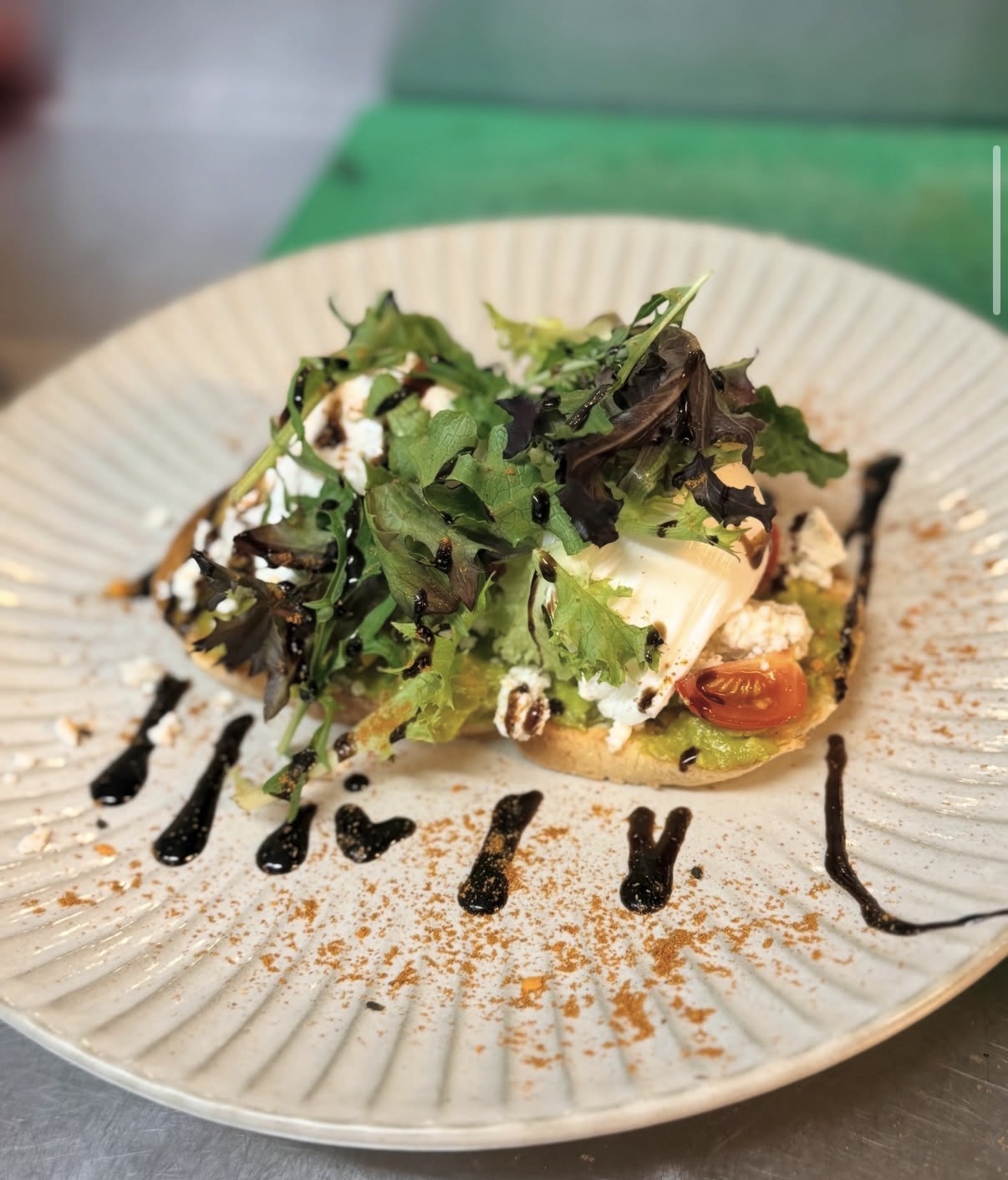 Avocado bruschetta with poached egg, feta and mixed leaves on a ceramic plate