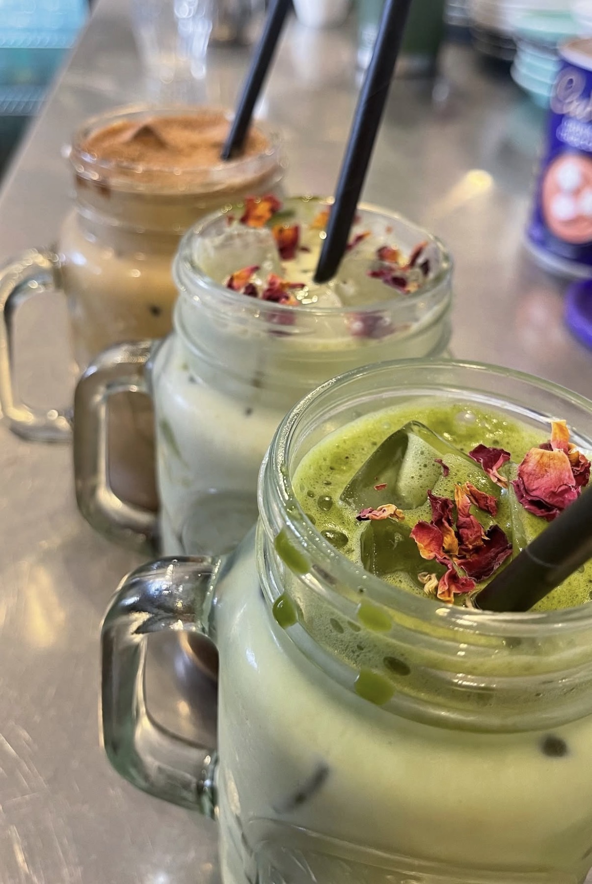Iced matcha lattes in glass jars topped with dried rose petals